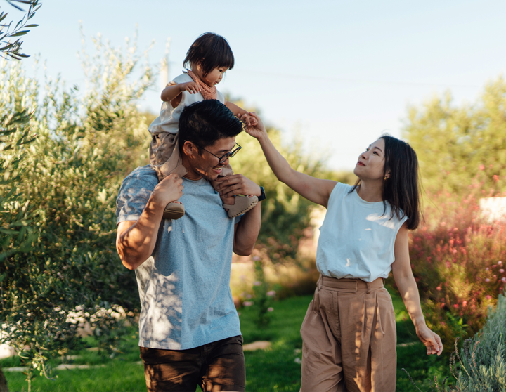 Eine junge Familie geht glücklich an einem sonnigen Tag an einem Waldstück spazieren