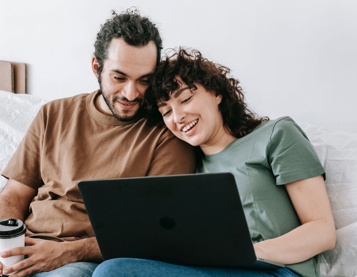 happy couple sitting infront of a laptop