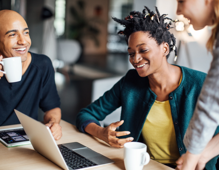 Three people laughing and looking at a screen talking about the benefits of debt collection