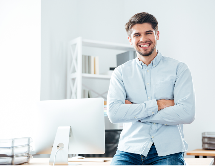 A smiling man standing next to his computer