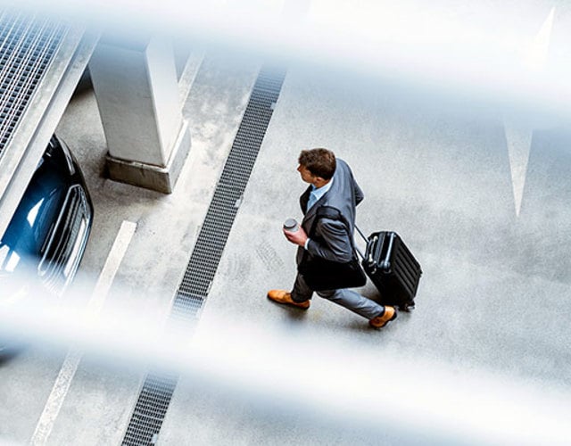 Man med rullväska går i ett parkeringsgarage