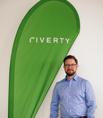 picture of Matthew Adamson in front of a Riverty flag
