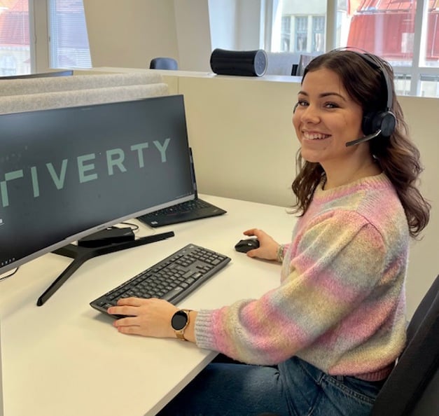 Thelma an ihrem Schreibtisch, mit dem ‘Riverty‘ Logo auf ihrem Bildschirm.