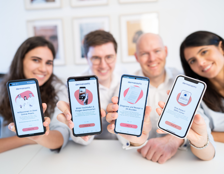 Fyra personer håller upp sina mobiltelefoner för att visa Dermanostic's app