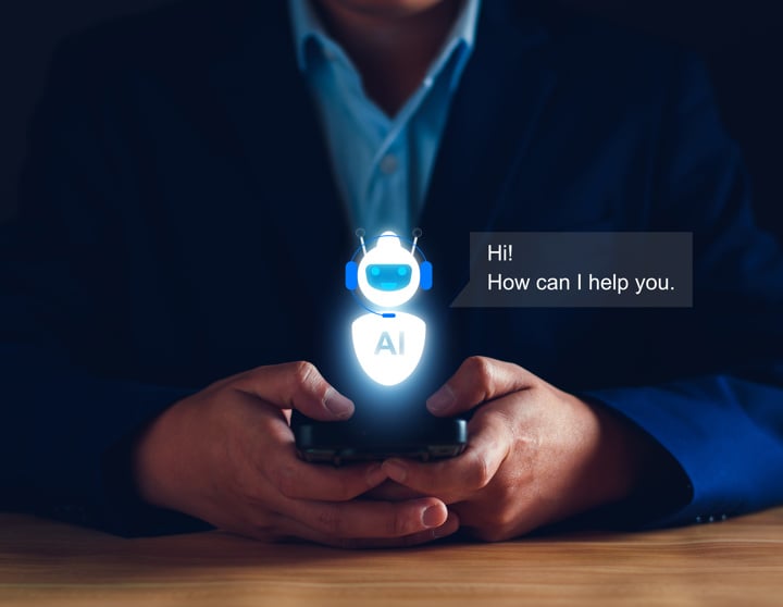A man in a suit holds a smartphone displaying a small robot on the screen.