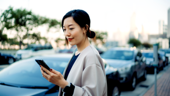 En kvinde, der står ved siden af sin bil og betaler parkering med sin mobil