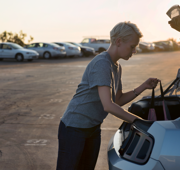 Nainen seisoo auton vieressä "free-flow"-pysäköintialueella 