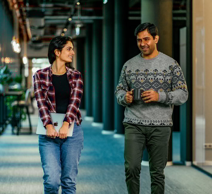 A female and a male riverty colleague talk to each other in the hallway