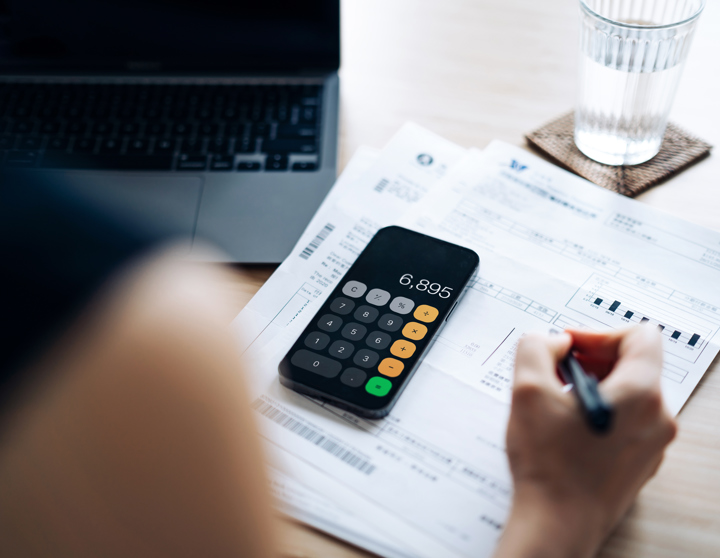 Person at desk with invoice and calculator 