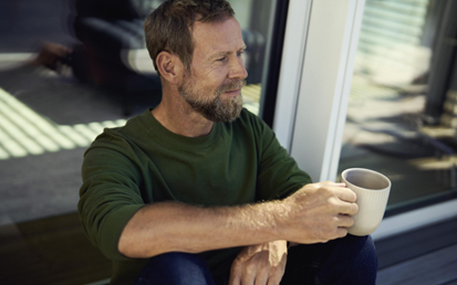 Mann auf einem Platz mit Kaffee in der Hand