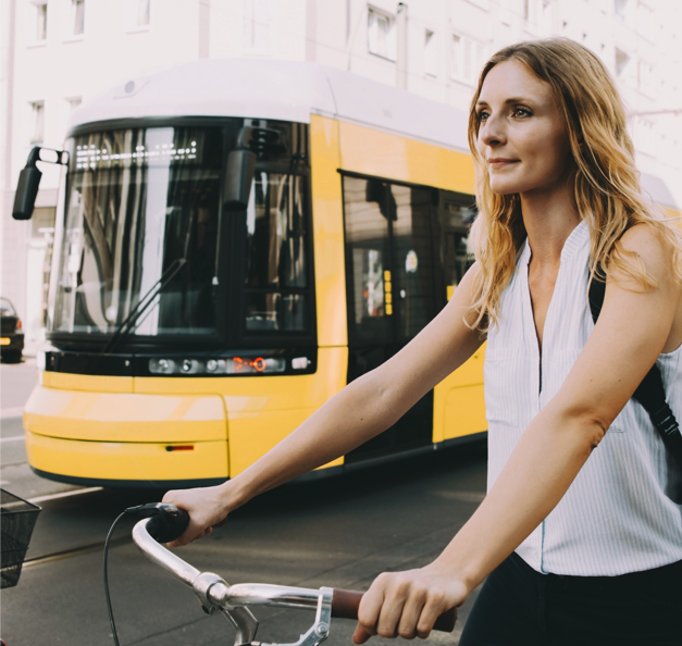 Frau auf Fahrrad neben Bahn