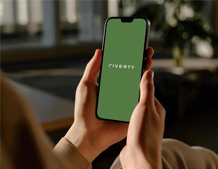 Riverty-Logo auf dem Handy-Display, gehalten in beiden Händen