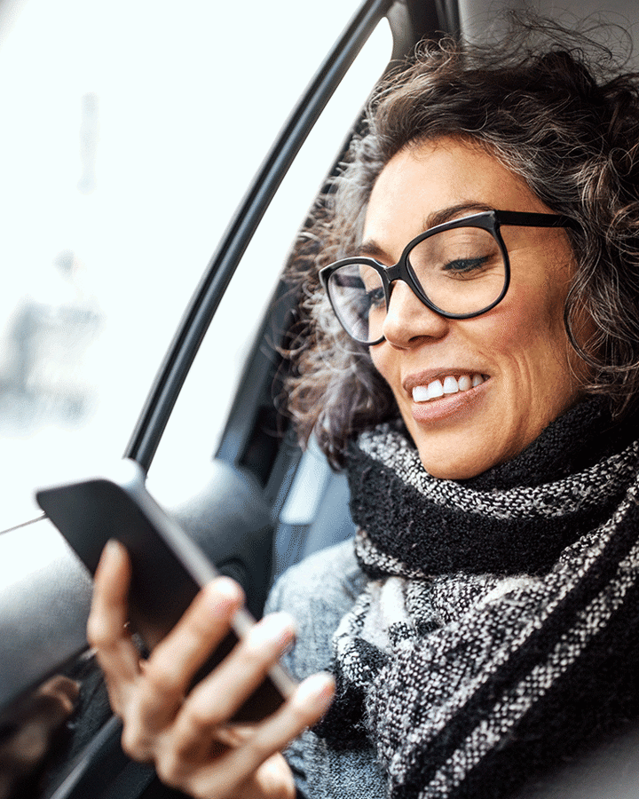 Een vrouw in een auto kijkt naar haar mobiele telefoon