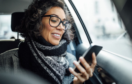 Image showing a woman who is sitting in her car and looking at her smartphone
