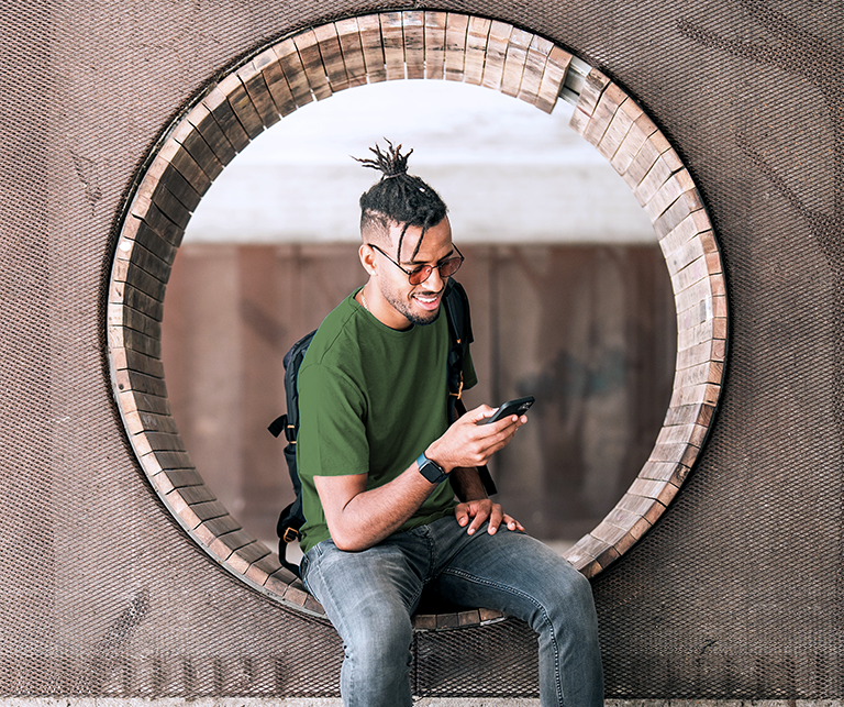 A man is sitting in a round window checking his mobile.