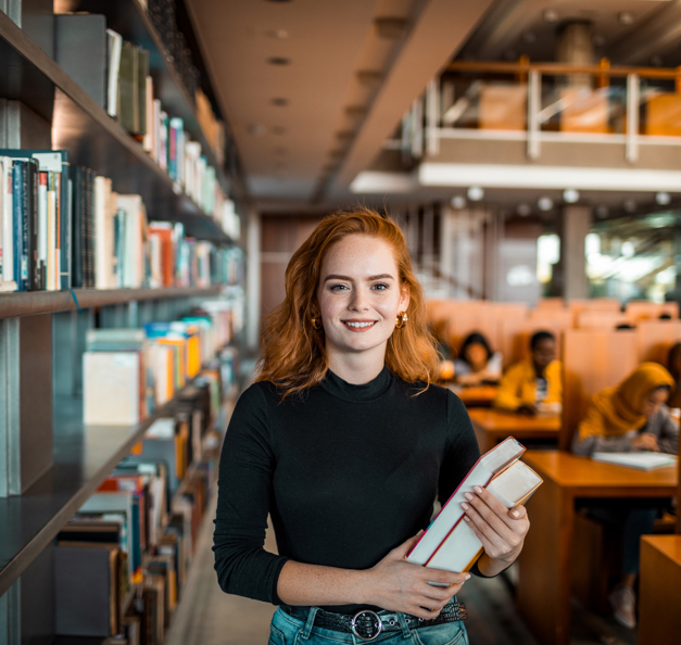 junge Dame in der Bücherei lächelt in die Kamera 