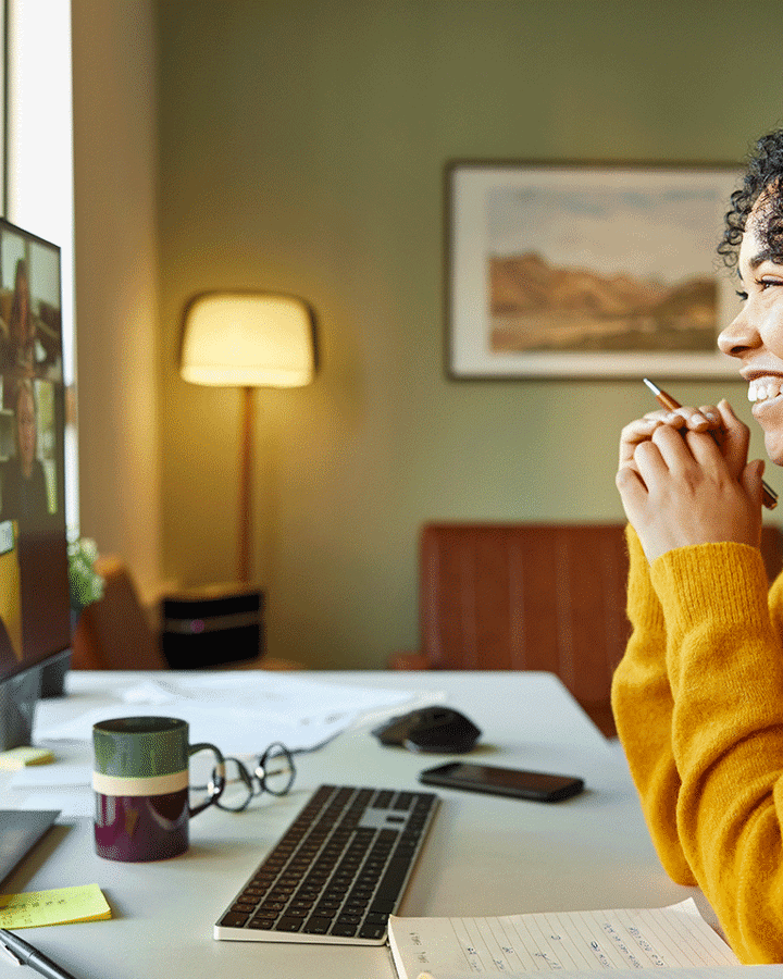 En kvinna i gul tröja sitter vid en dator