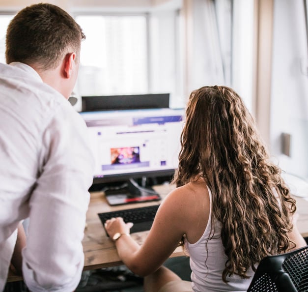 a young man is explaining something to a student in front of her laptop