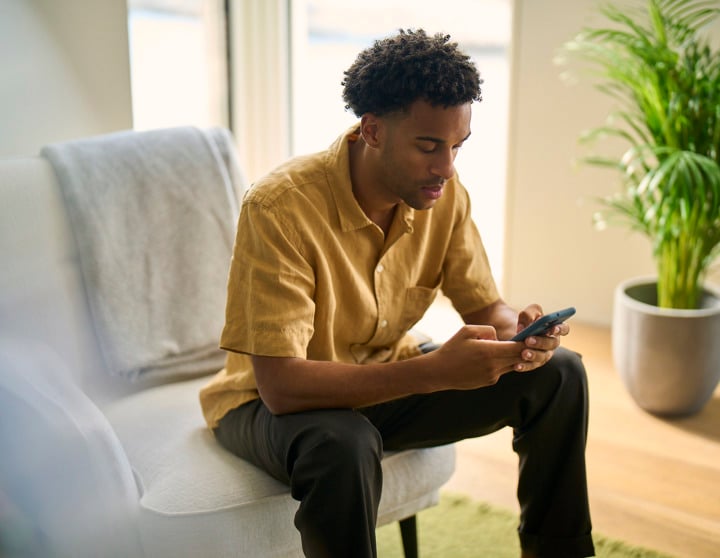 A man is sitting on a chair and looking at his phone