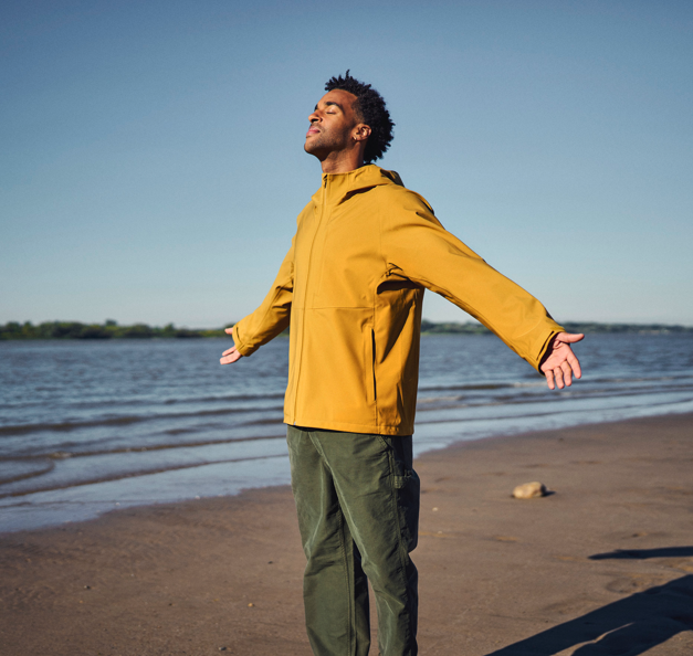 Man who is wearing a yellow jacket standing on the beach