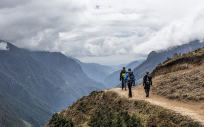Ein Foto dreier Wanderer, die einen Weg entlang gehen mit Blick auf ein weites Tal