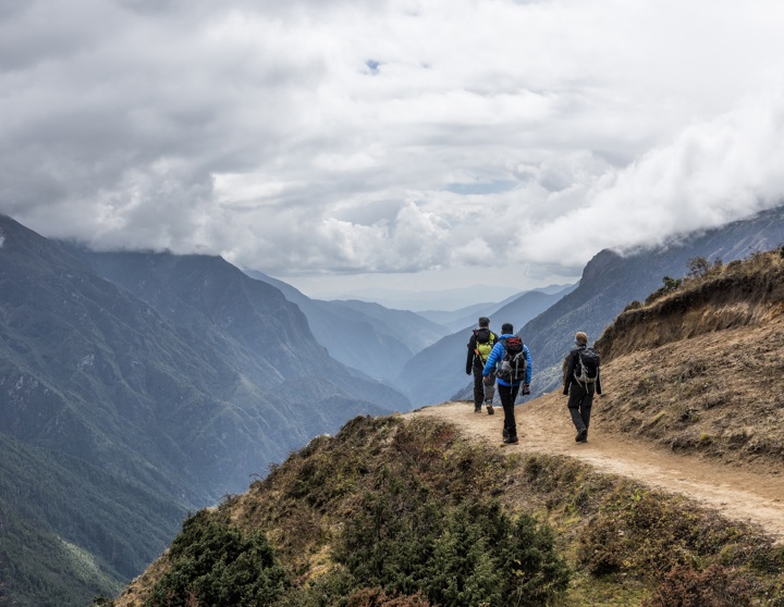 Ein Foto dreier Wanderer, die einen Weg entlang gehen mit Blick auf ein weites Tal