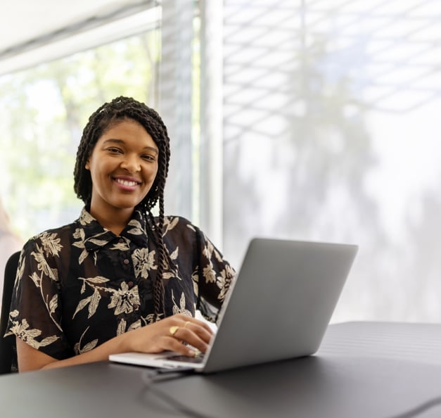 young woman in front of her laptop smiling