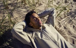 En man ligger på en strand och tittar upp i himlen
