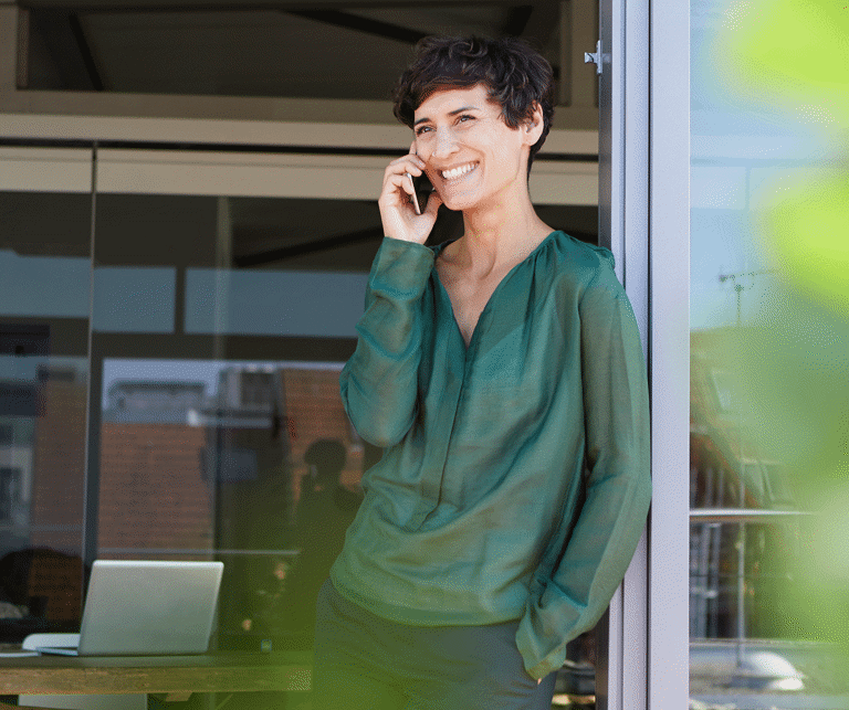 Eine Frau steht am Fenster und telefoniert.