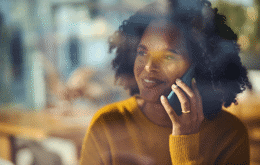 Kvinne i gul genser som smiler og snakker i telefonen