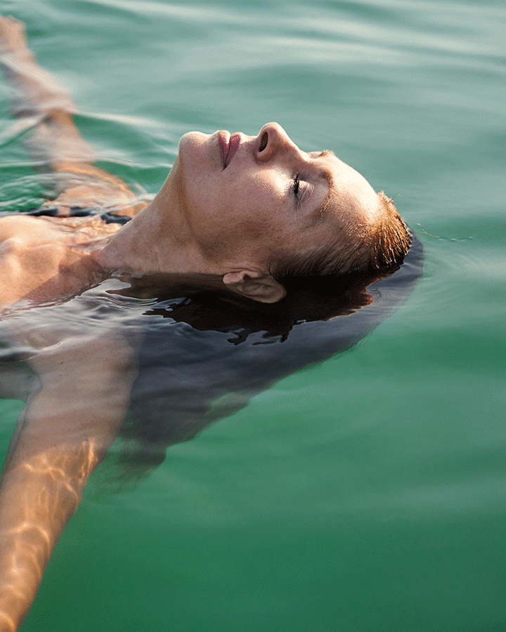 En kvinna ligger i vatten och flyter