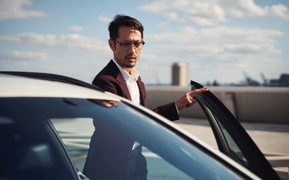  A man with glasses standing next to a car