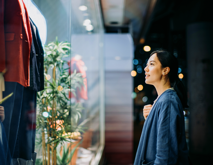 Frau, die ein Schaufenster eines Modegeschäfts betrachtet