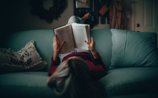 Vrouw zit op de bank en leest een boek tijdens de winter