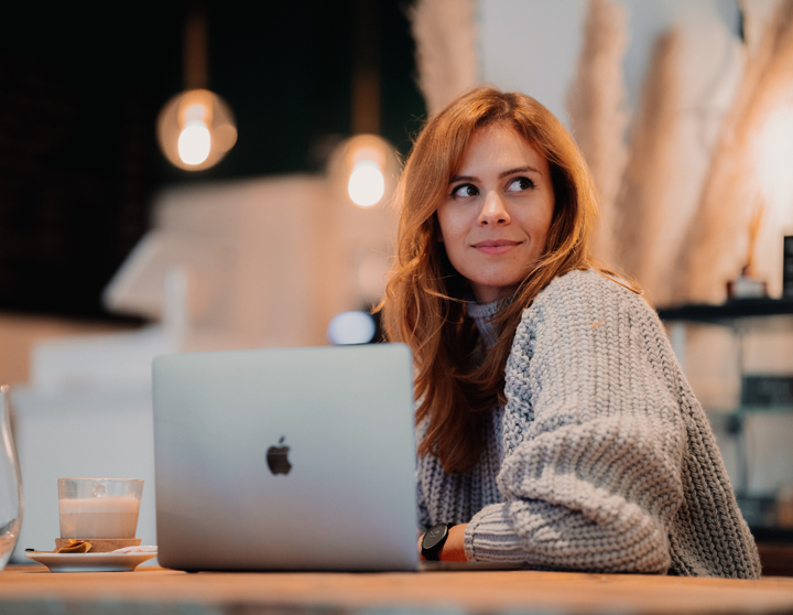 Eine junge Frau sitzt am Tisch vor ihrem Laptop und erinnert sich an das Jahr zurück