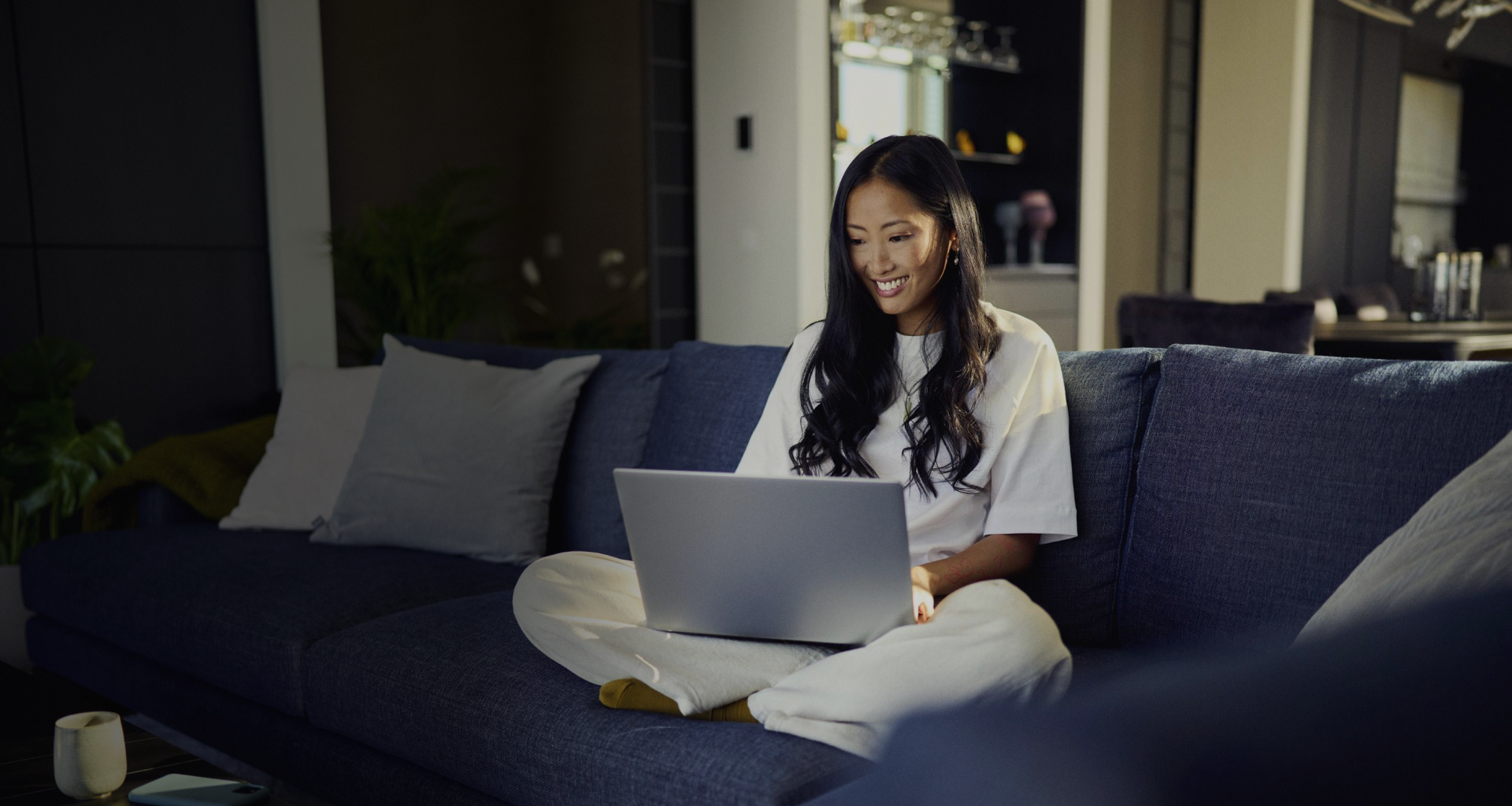 Woman in her home, sitting on a couch shopping online and using Riverty Pay in 3