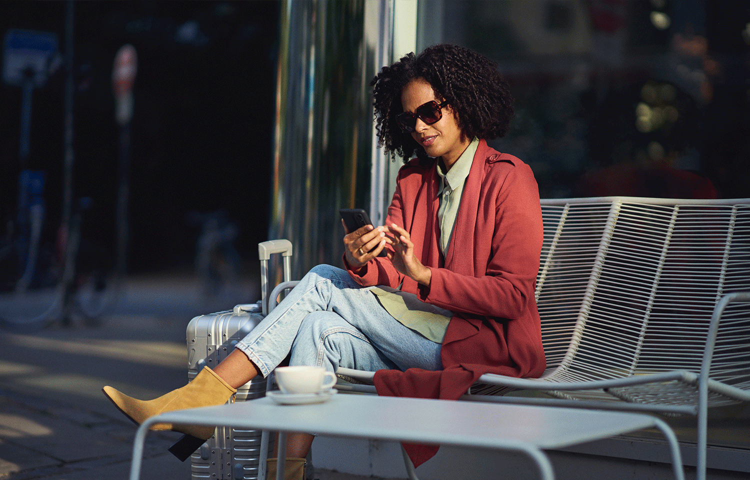 Nainen istuu penkillä ja katsoo puhelinta