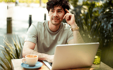 Een man zit buiten achter zijn laptop na te denken