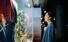 Woman in front of a store, looking at the retailer's offerings through a shop window.