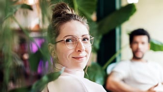 Man and woman sitting next to each other on a couch, surrounded by plants