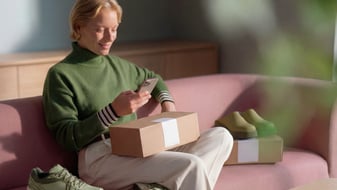 A woman is sitting on the couch and looking at her phone.