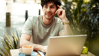Een man zit buiten achter zijn laptop na te denken