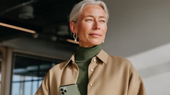 Woman with gray hair holding a smartphone indoors