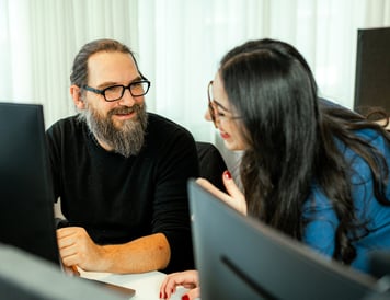 Two colleagues smiling and discussing ideas in a collaborative work environment