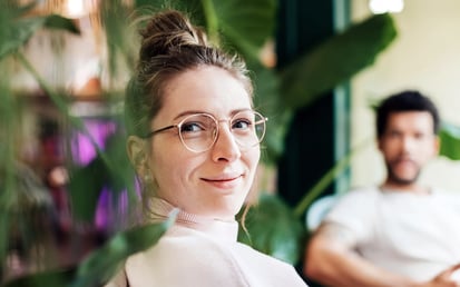 Man and woman sitting next to each other on a couch, surrounded by plants