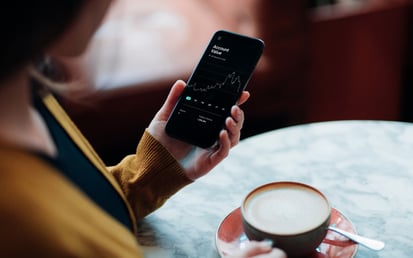 Person mit Handy und Kaffee in der Hand