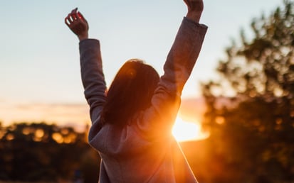 A woman with her hands in the air during golden hour