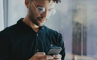 Junger Mann, der sein Smartphone in der Hand hält