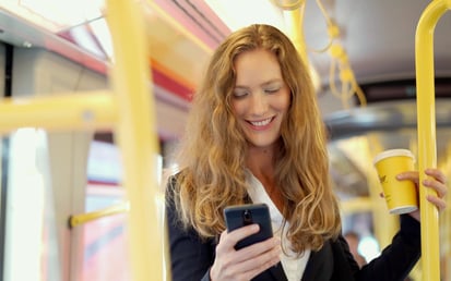 Frau mit einem Handy fährt in einem Bus