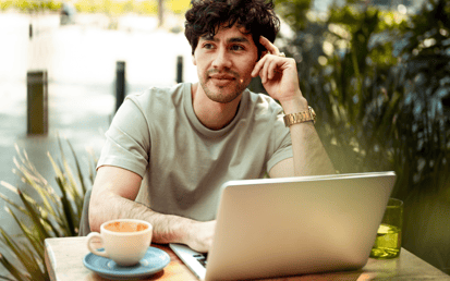 Een man zit buiten achter zijn laptop na te denken